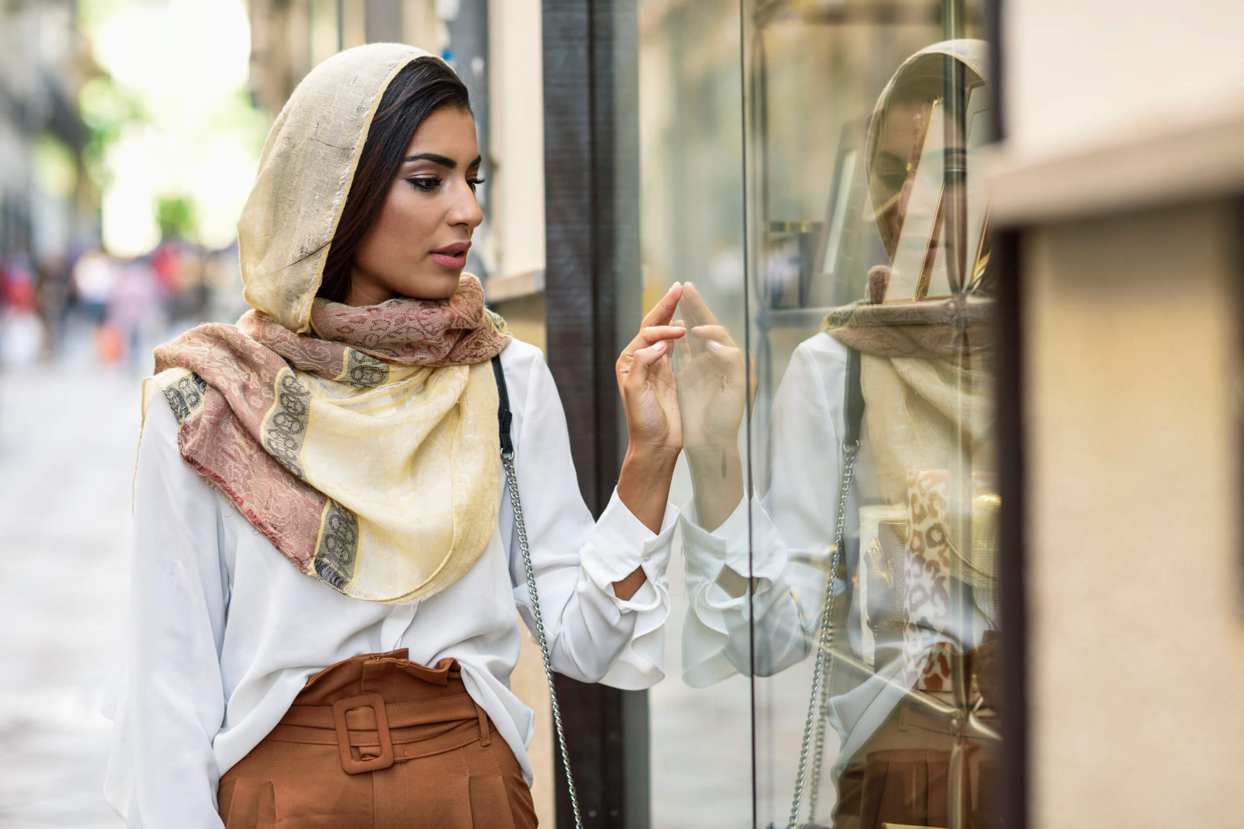 Spain, Granada, young muslim tourist woman wearing hijab looking at shop windows on a shopping street